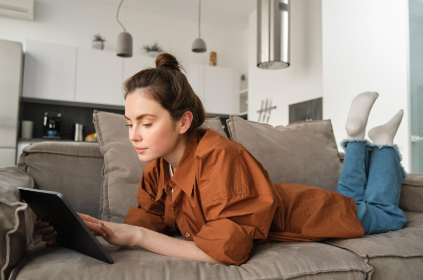 Person browsing a tablet on a couch, illustrating relaxed weekend planning and search behavior.