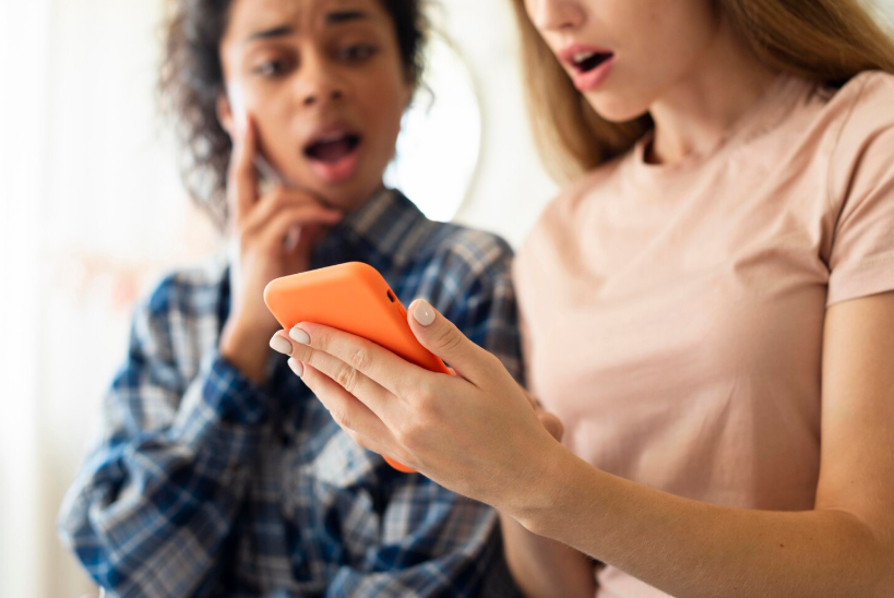 People reacting to surprising information on a phone, illustrating rumor driven search spikes.