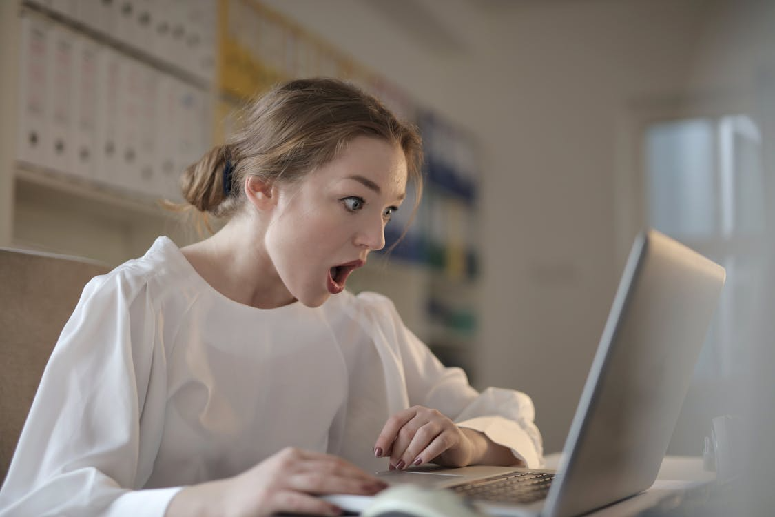 Person reacting with shock while searching online, illustrating fear driven search behavior.